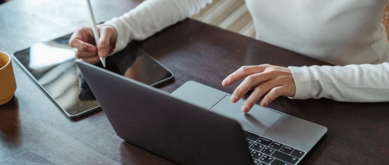 crop faceless female entrepreneur doing multitasking work on different devices